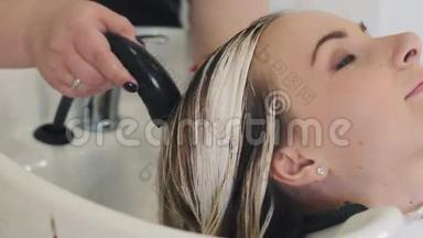 理发师在美容工作室洗`女人的头发，水疗中心和健康的头发面具，美容治疗，女人在水疗中心。